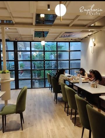 Dining room with green chairs and tall windows